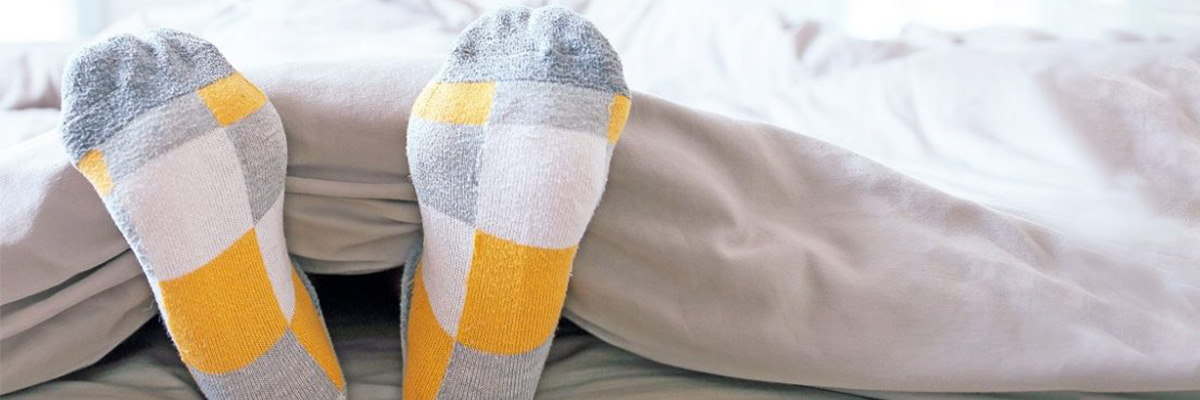 Close up of feet with socks stretching lazily in Bed