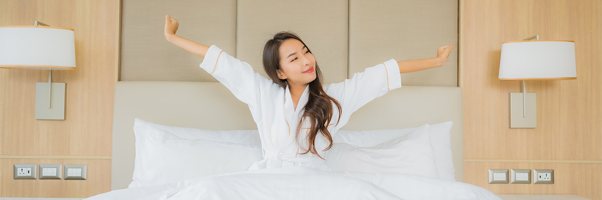 Young Woman Stretching iin the bed after waking Up