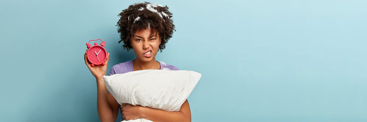 Woman Holding a Clock and a pillow After Waking Up